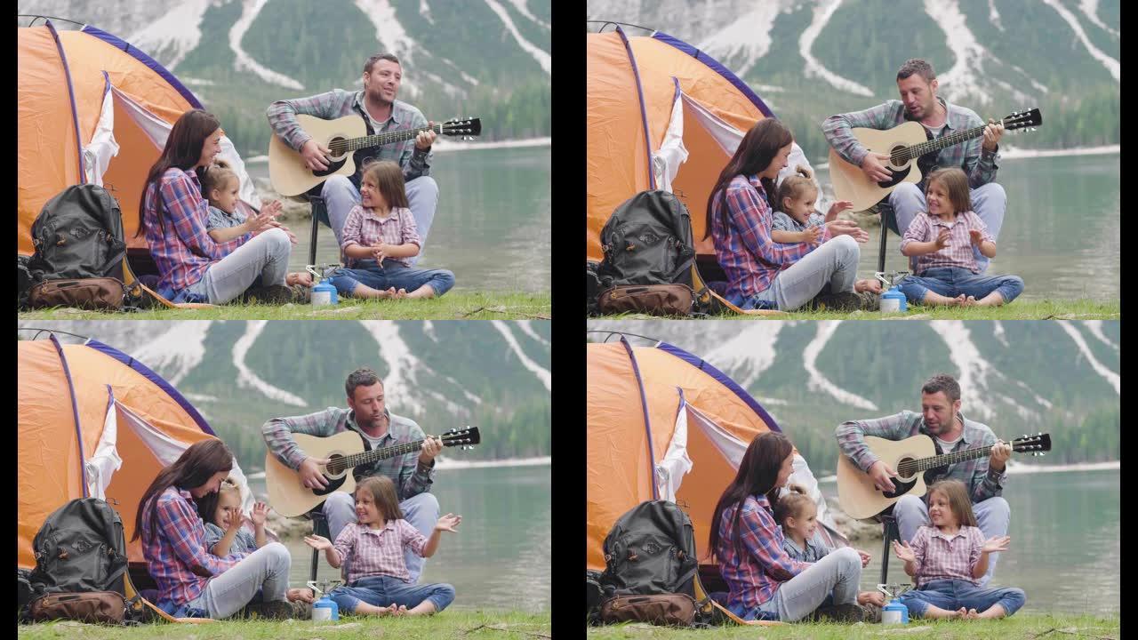 一个幸福的家庭在湖边露营，弹吉他，一起在帐篷前唱歌。