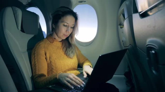 飞机机舱内有一位女士在飞行中使用笔记本电脑