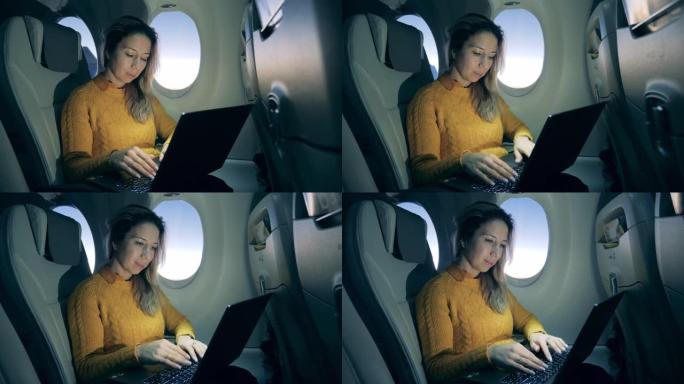 飞机机舱内有一位女士在飞行中使用笔记本电脑