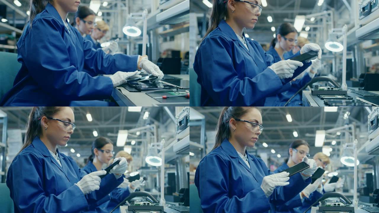 穿着蓝色工作服和防护眼镜的女电子工厂工人拿起智能手机屏幕并进行质量检查。拥有多名员工的高科技工厂设施