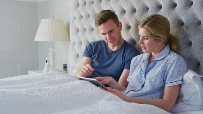 在Covid 19锁定期间，夫妇在床上使用数字平板电脑进行自我隔离