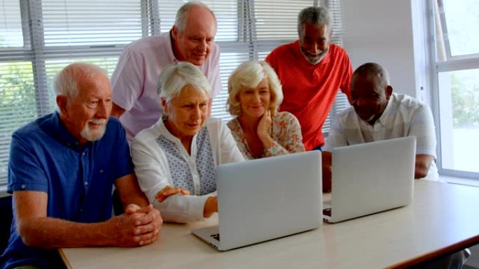 在养老院使用笔记本电脑的活跃混血老年人的前视图4k