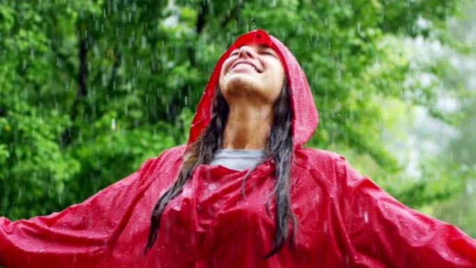 一个快乐的女人在雨中微笑，女人沉浸在快乐自由的雨中慢动作下的舞蹈中。