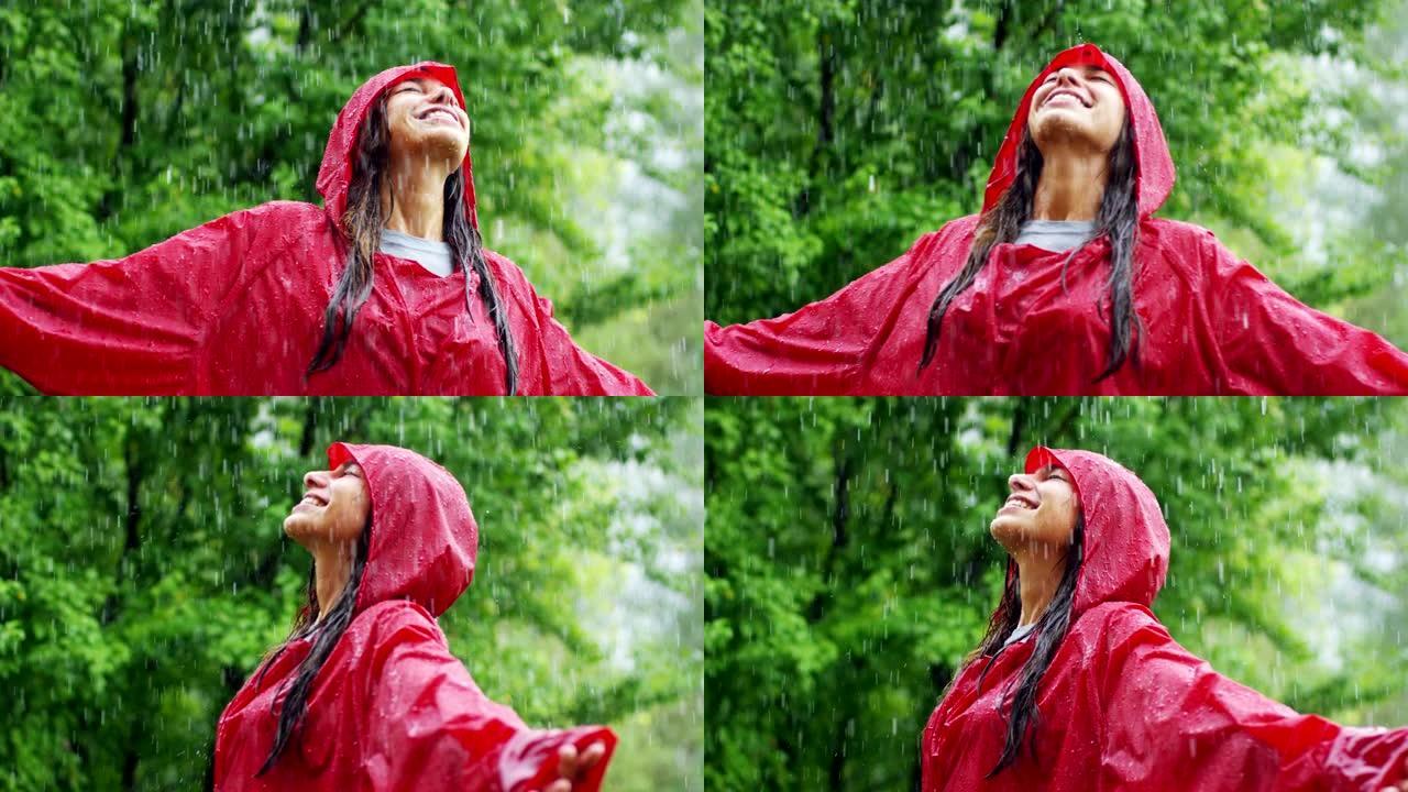 一个快乐的女人在雨中微笑，女人沉浸在快乐自由的雨中慢动作下的舞蹈中。