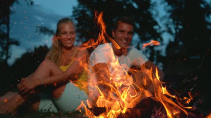 特写: 当旅游夫妇坐在附近时，火花从篝火中飞出。