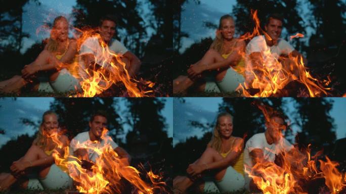 特写: 当旅游夫妇坐在附近时，火花从篝火中飞出。
