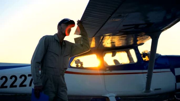 一个人看着日落背景上的双翼飞机，特写。