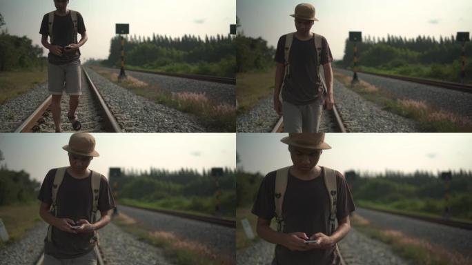 一个年轻人在铁路上行走时使用手机