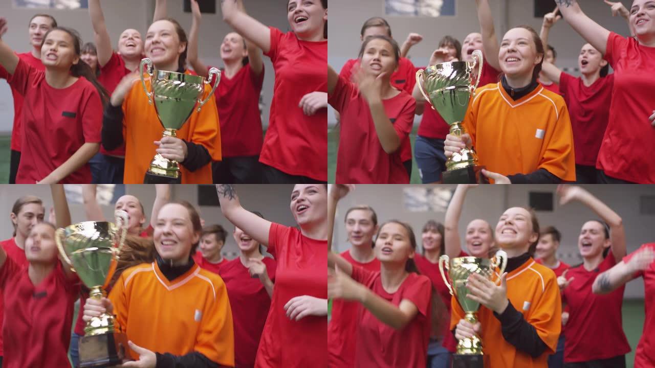 快乐的足球女队带着杯子离开运动场