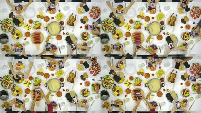 一群朋友在晚宴上与桌子上的所有人一起使用他们的智能手机拍摄晚餐食物的照片。Instagram，社交网