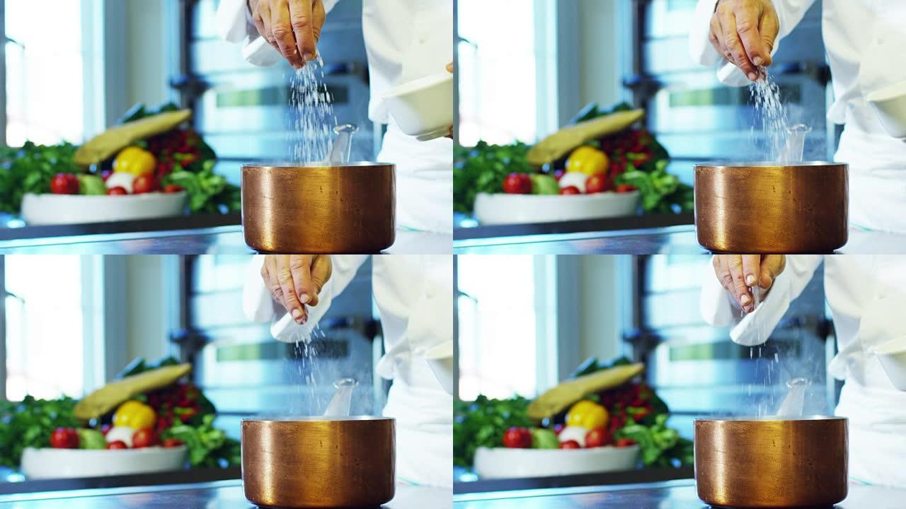 在意大利专业厨房中，厨师将盐倒在盘子或水中，以煮沸意大利面食的健康和清淡食品概念。
