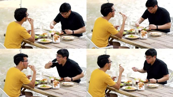 在泰国清迈Stream的Nature Restaurant赤脚吃午餐的两个男人朋友的倾斜镜头