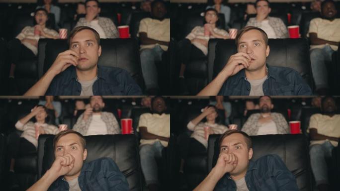 受惊的人在电影院里吃爆米花看恐怖恐怖电影