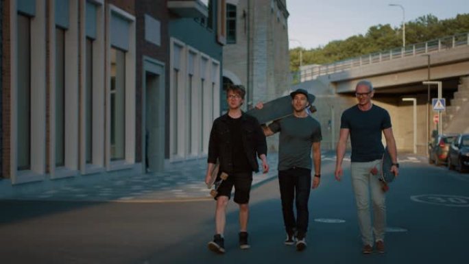 三个很酷的家伙说话，边走边玩，边提滑板。时尚的年轻朋友在街上漫步。背景时尚现代潮人区