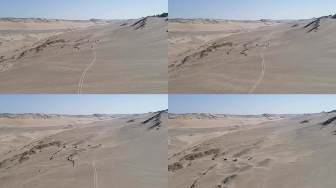 纳米比亚纳米布沙漠骨架海岸上4x4车辆在沙丘和山脉之间行驶的车队的4k空中后视图