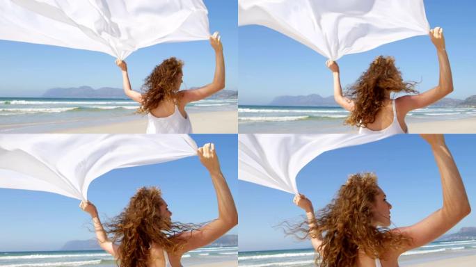 女人站在海边，挥舞着围巾。在海滩4k