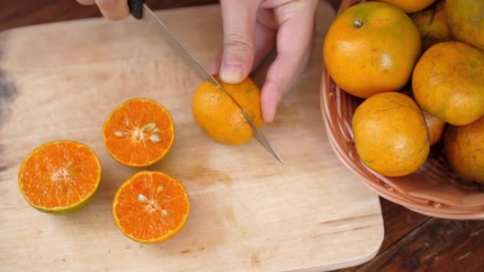 女人用手切割橙色水果以获取新鲜橙汁，慢动作