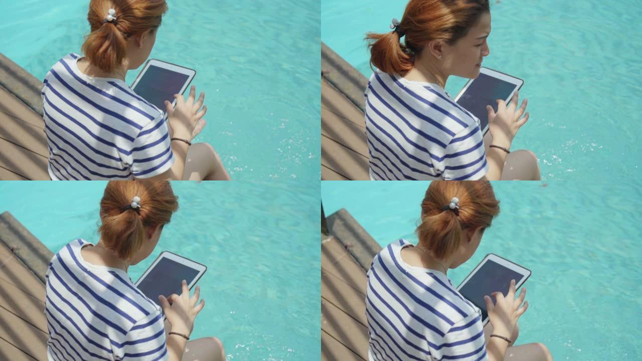 使用数字平板电脑坐在游泳池附近的女性，慢动作