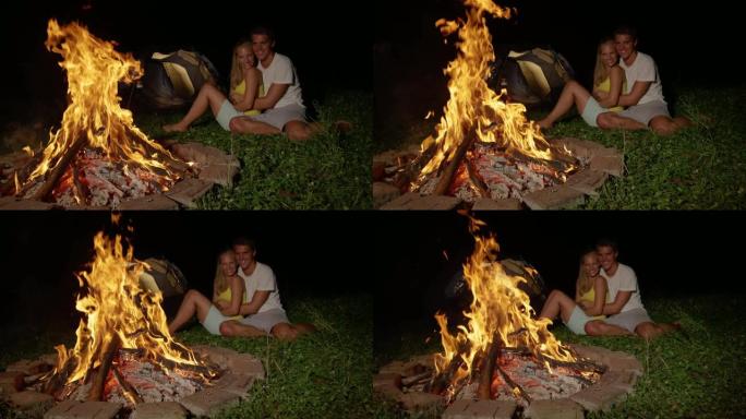 特写: 开朗的高加索夫妇坐在温暖的篝火旁拥抱。