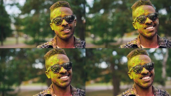 快乐的非洲裔美国人家伙时髦的特写肖像看着相机，在胡里节上微笑着，脸上和头发都被粉末涂料弄脏了。人和传