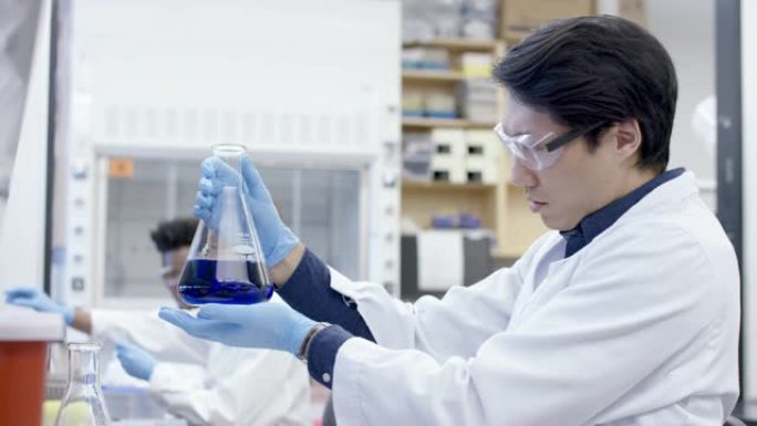 男化学家在科学实验室中分析流体