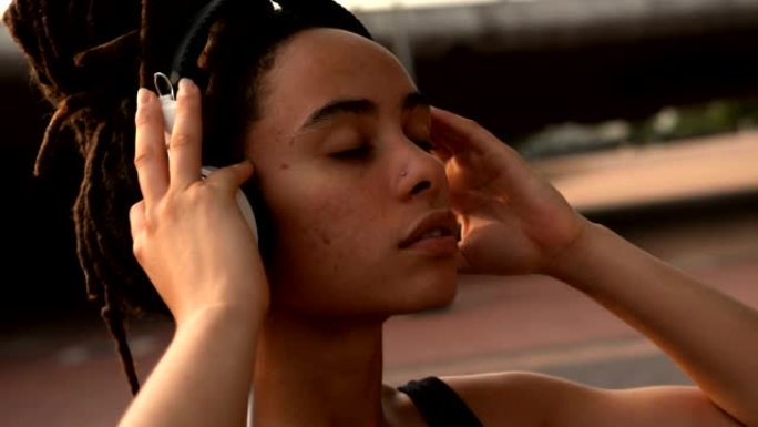 城市4k中年轻的非洲裔美国妇女在耳机上听音乐的前视图