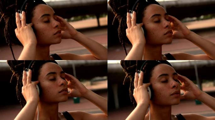 城市4k中年轻的非洲裔美国妇女在耳机上听音乐的前视图