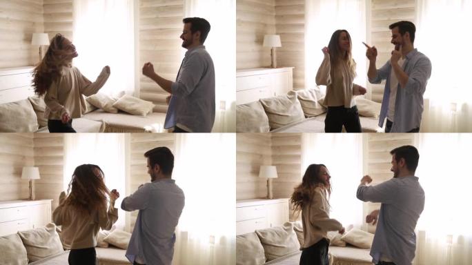 年轻无忧无虑的活跃情侣在家客厅跳舞