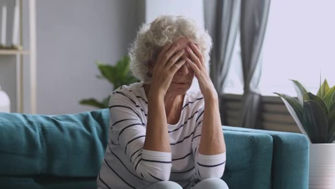 沮丧的成熟女人在家里头疼得厉害。