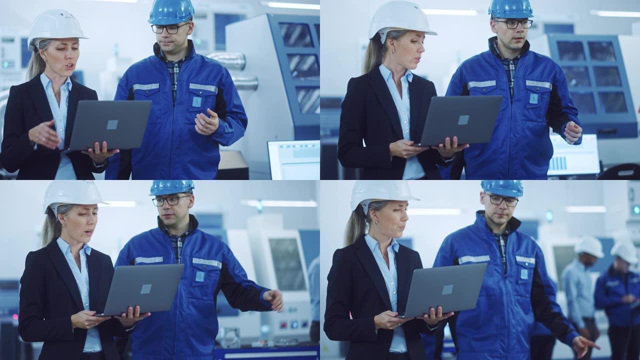 女经理和项目工程师戴着安全帽穿过工业工厂，使用笔记本电脑，交谈，计划生产率优化。生产线工人操作数控机