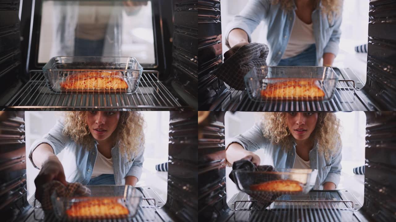 当女人烹饪烤箱烤鲑鱼时，从烤箱内看