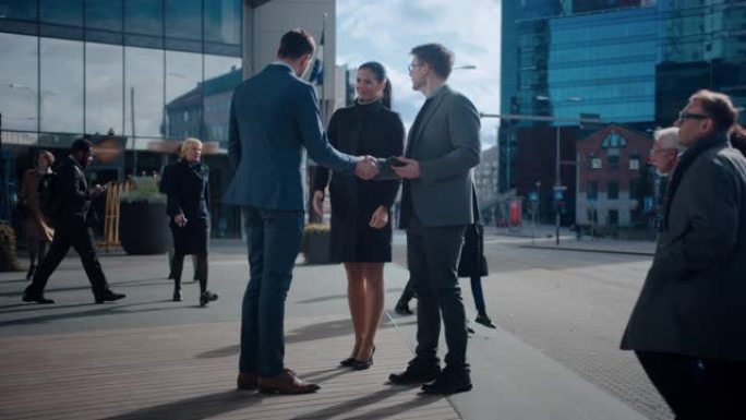 多元文化的办公室经理和商人走在街上。男女在商务中心旁边遇到一个公司合作伙伴并握手。