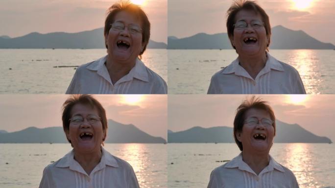日落时在美丽的大海前笑的亚洲高级女性肖像。人，假期，健康，生活方式，退休，肖像，旅行。高级肖像