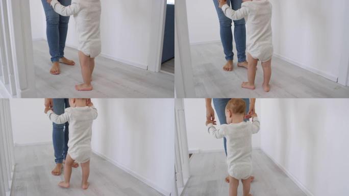 赤脚蹒跚学步的孩子在支持下学习走路