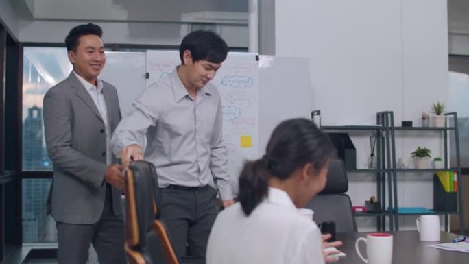 一群年轻的亚洲商人在夜间办公室的会议室进行交易并签署合同或协议后庆祝握手。