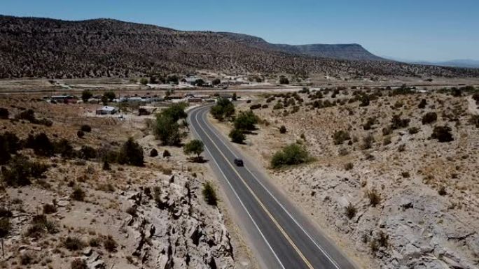 美国亚利桑那州夏季，无人机跟随银色小型货车沿着美丽的沙漠山路行驶。公路旅行概念。