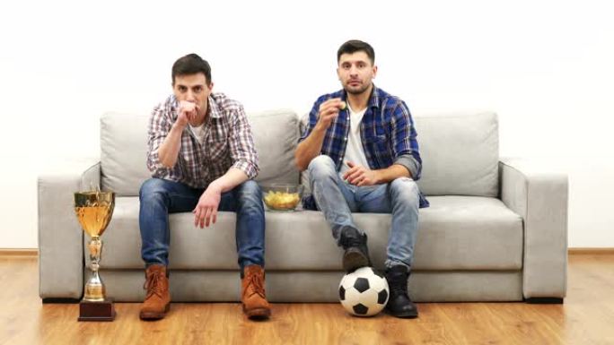 两人在沙发上看足球吃薯条