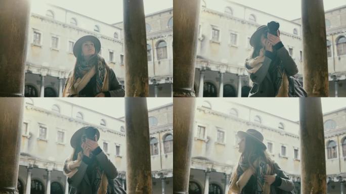 快乐的职业女记者用相机在威尼斯老城古建筑用古董柱子拍照