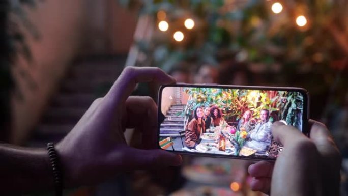 用朋友用餐的智能手机拍照的特写男人
