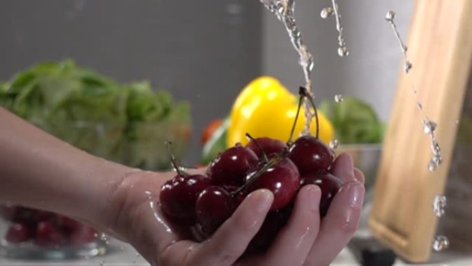 超级慢动作女人在流水下洗手新鲜樱桃。冲洗成熟的红樱桃