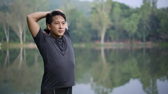 英俊的运动亚洲男子在使用稳定设备进行锻炼之前进行全身伸展运动