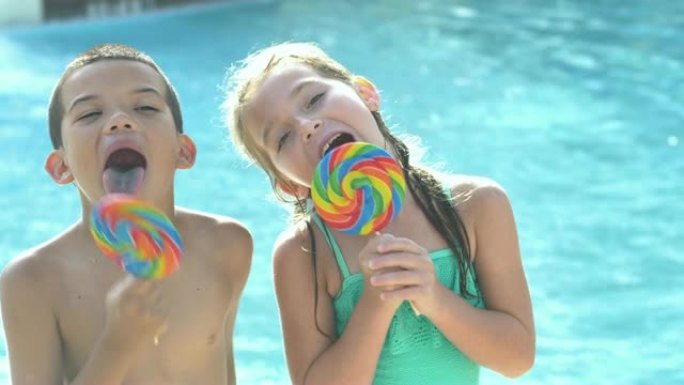 男孩和女孩在游泳池享受棒棒糖