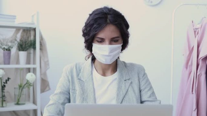 生病的年轻女商人戴着电脑咳嗽的口罩
