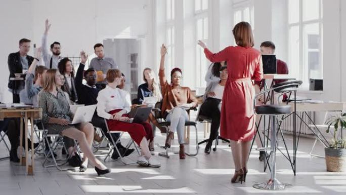 女教练领导研讨会，多民族观众聆听并举手现代时尚办公室红色史诗慢动作。