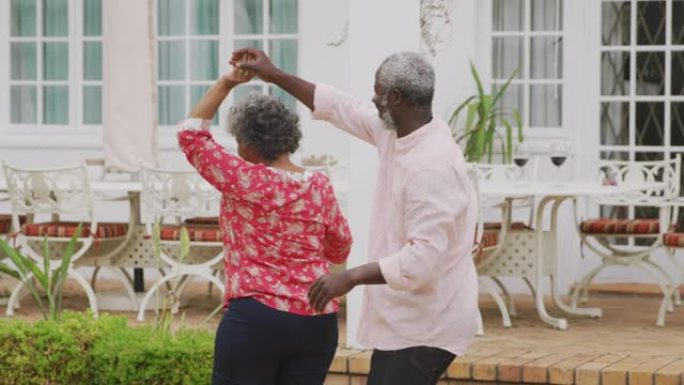 一对资深的非洲裔美国夫妇在一起度过时光，在花园里跳舞。