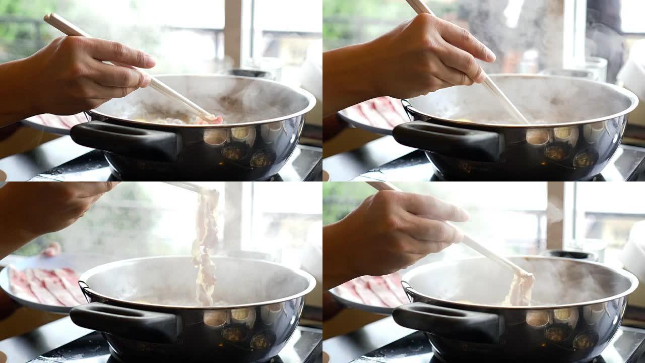 4k镜头用筷子、sha锅和Sukiyaki搅拌的煮汤火锅中蘸肉片的场景日式美食概念