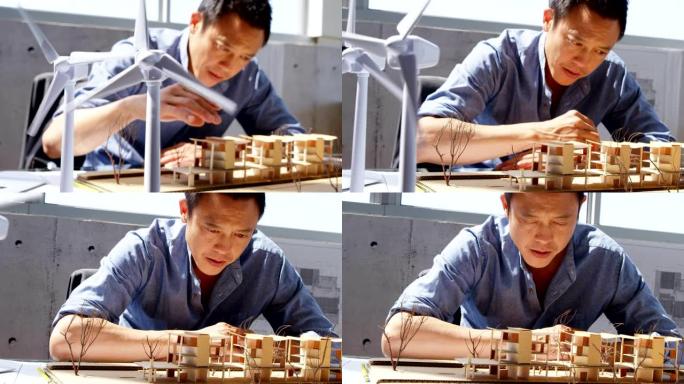 亚洲男建筑师在现代办公室4k中观察建筑模型的前视图