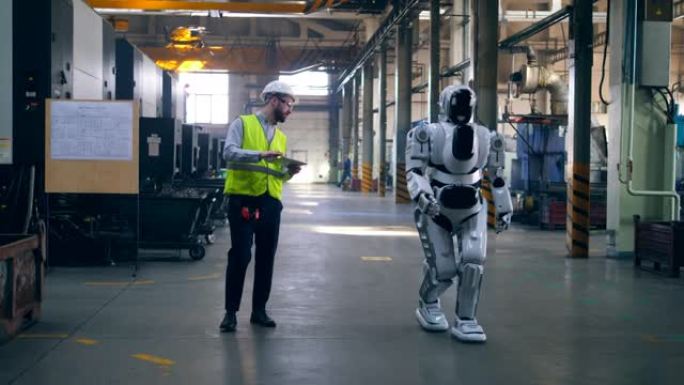 类似人类的机器人和一名男性技术人员正在行走