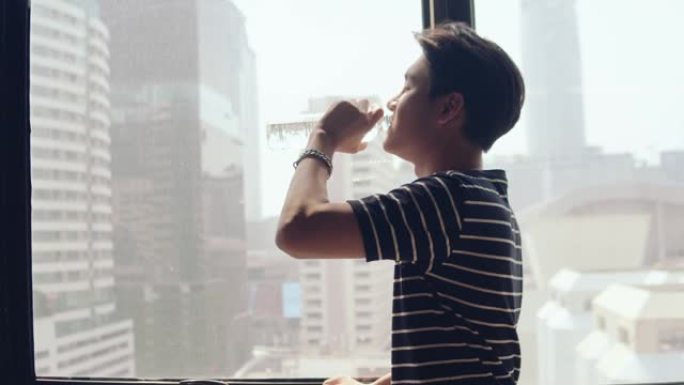 年轻的亚洲男子用玻璃喝水。