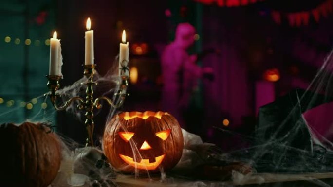 万圣节静物感丰富多彩的主题: 可怕的装饰黑暗的房间，桌子上覆盖着蜘蛛网，燃烧的南瓜，烛台，女巫的帽子